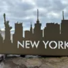 Silueta metálica Nueva York con Estatua de la Libertad sobre roca